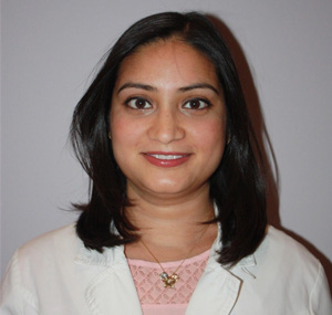 A woman with short hair wearing a white jacket smiling directly at the camera.