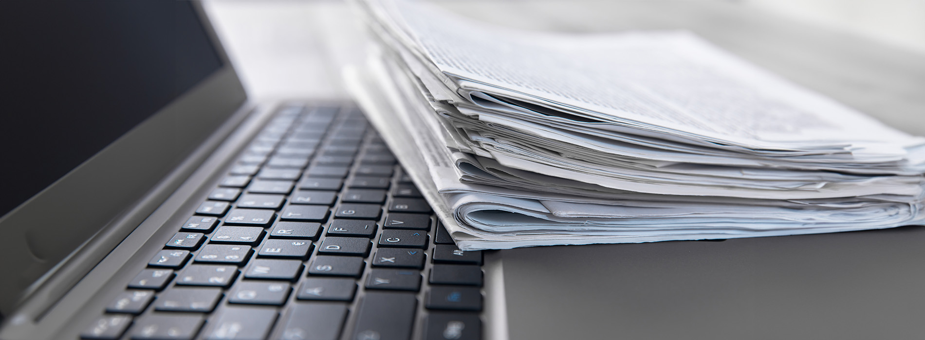 The image shows a stack of papers on top of a laptop keyboard.