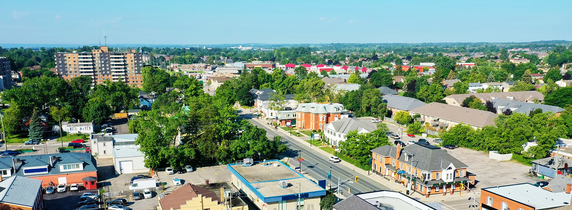 The image shows an aerial view of a neighborhood with houses, streets, and trees during daylight hours.