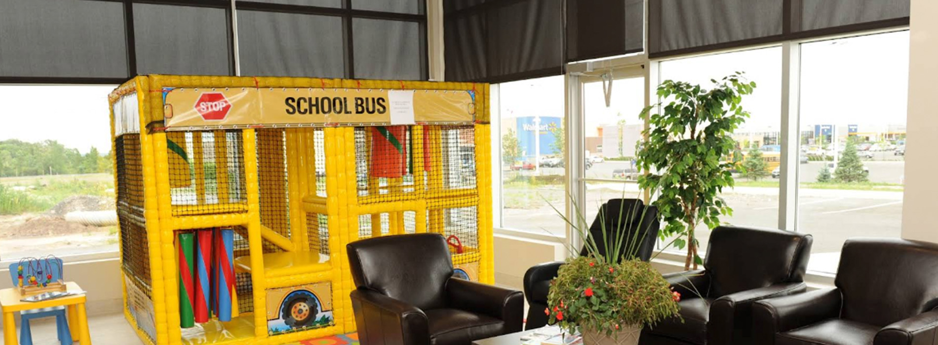 The image shows an indoor space with a black couch, a yellow play area structure, and a sign indicating it s a school bus theme room.
