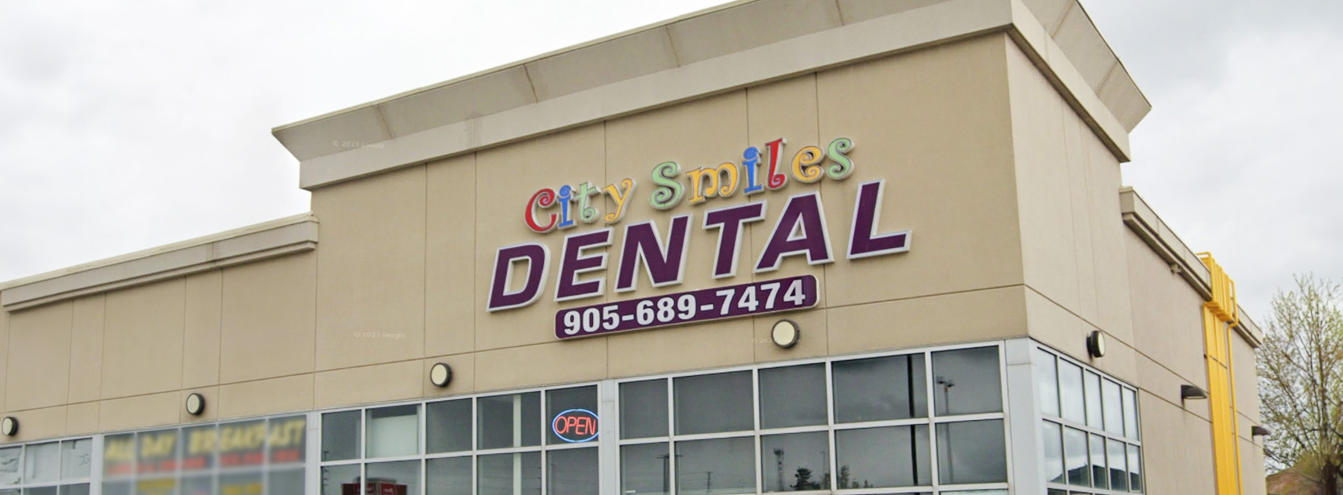 The image shows a dental clinic with an exterior sign indicating its name and services.