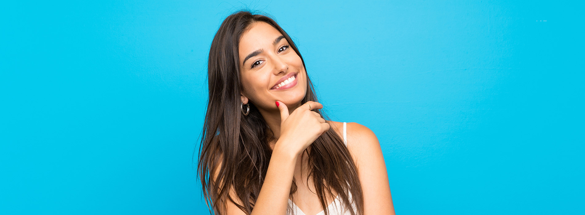 A woman with long hair smiling at the camera against a blue background.