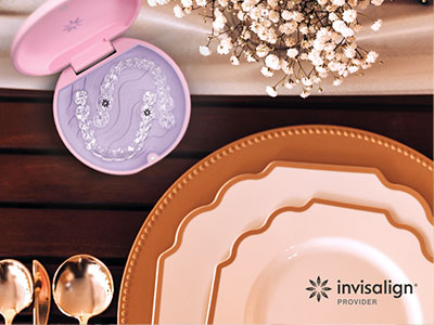 The image displays a collection of tableware including plates, bowls, and a cake tin, with a focus on a small purple object that appears to be a toothbrush holder, set against a background with various items such as a vase, spoons, and a cake stand.