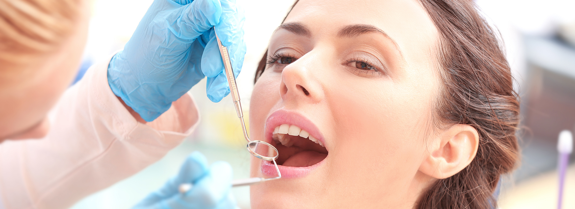 A woman receiving dental care with a team of professionals around her, focusing on her mouth.