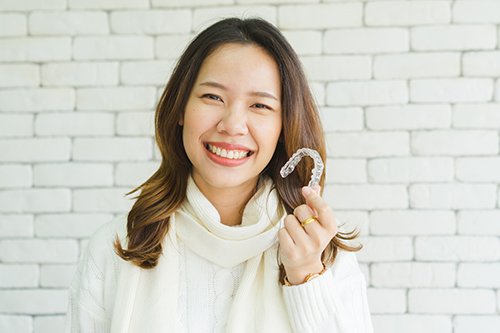 A woman holding a toothbrush with a smile on her face, posing for a photo.