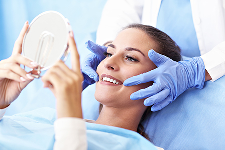Woman receiving beauty treatment with magnifying mirror held by professional, possibly in a dermatology or skincare clinic setting.