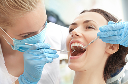 The image shows two individuals in a dental setting one person appears to be receiving dental care while another person, possibly a dentist, is working on their teeth using dental instruments.